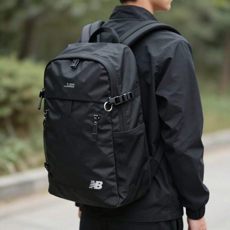 검정색 뉴발란스 플라잉폼 백팩을 등에 멘 모습. 가방 측면에 키링이 달려 있고, 간결한 디자인이다.