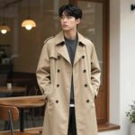 나이스클랍 트렌치코트를 입은 사람이 카페 앞에 서 있는 모습