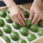 향긋한 봄 쑥으로 만드는 집에서 쑥개떡 레시피 쑥개떡 반죽을 손으로 치대고 있는 모습, 진한 초록색의 매끈한 반죽