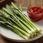 싱싱한 두릅 나물이 접시에 담겨 있고 옆에 초고추장이 놓여 있는 모습