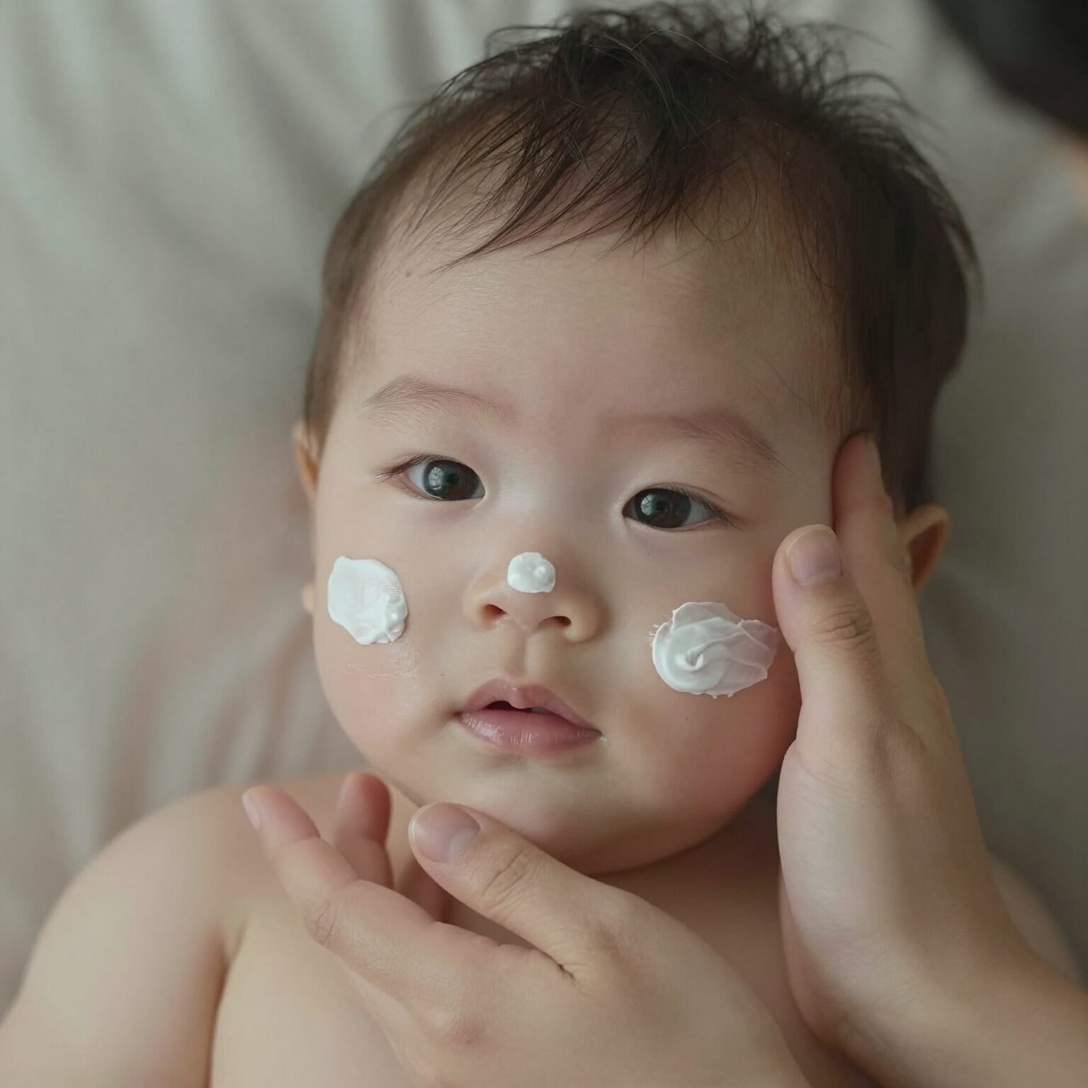아기 얼굴에 선크림 바르는 엄마 손