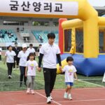 군산대학교 대운동장 어린이날 행사 현장 사진. 가족 마라톤 출발선과 에어바운스 부스가 보인다.