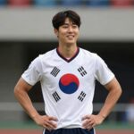 오현규 선수가 슈투트가르트 유니폼을 입고 포즈를 취하며 웃고 있는 모습